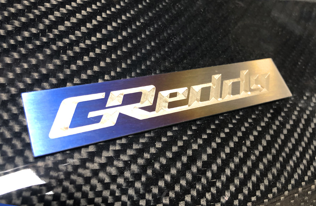 GREDDY TI PLENUM EMBLEM (105x20MM) - (18000201)